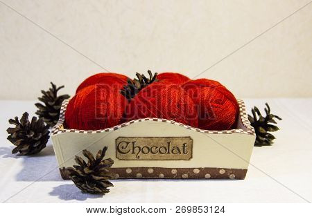 Red Yarn For Knitting In A Basket And Pine Cones On A White Background. Basket With Balls Of Wool. R