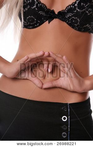 Ragazza mano nella mano in forma di cuore sulla pancia