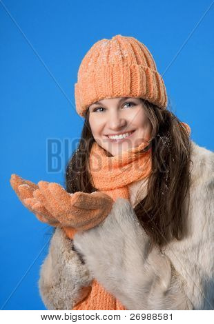 Picture of a beautiful brunette girl in the orange cap and coat on a blue background