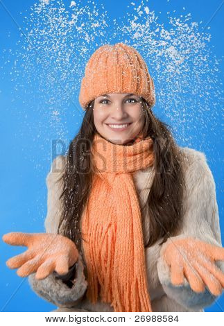 Picture of a beautiful brunette girl in the orange cap and coat on a blue background