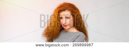 Charming Young Girl With Red Hair. A Young Girl In A Gray Sweater. Young Girl On A Gray Background. 