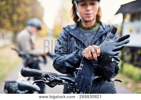 Active Senior Couple With Electrobikes Standing Outdoors On A Road In Nature.