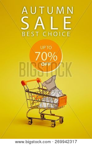 Close Up View Of Little Shopping Trolley With Paper Clothes On Yellow Backdrop, Ssss Inscription