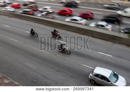 Pan Shoot Of Motorcycles At High Speed On An Avenue In Downtown From A Nearby Building With Slower C