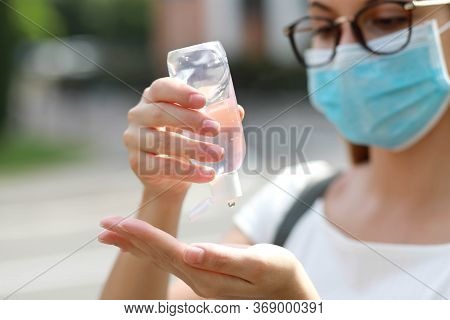 Close Up Of School Girl With Medical Mask Using Hand Sanitizer Gel In City Street. Antiseptic, Hygie