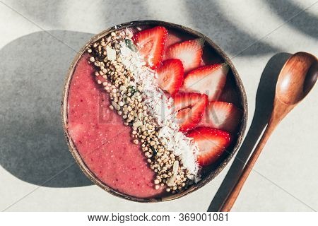 Pink Smoothie From Banana And Strawberries With Pieces Of Strawberries, Granola And Coconut Shreds O