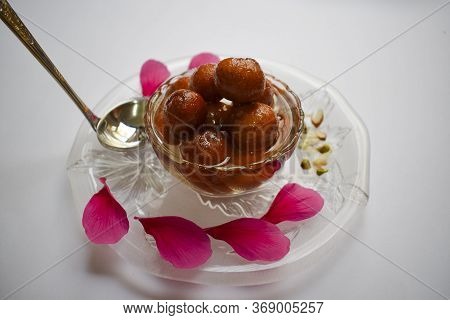 Side View Close Up Of Heap Of Gulab Jamun Decorated With Petals And Garnished With Dry Fruits.popula