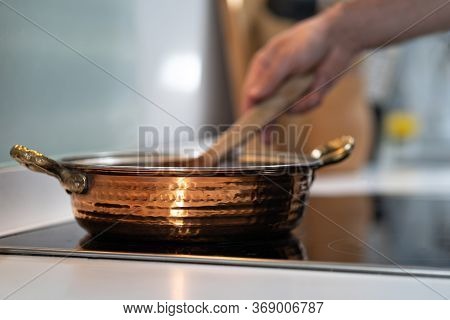 Vintage Textured Copper Cooking Pot On Kithcen With Male Hand Cooking Mixing Food In Pot