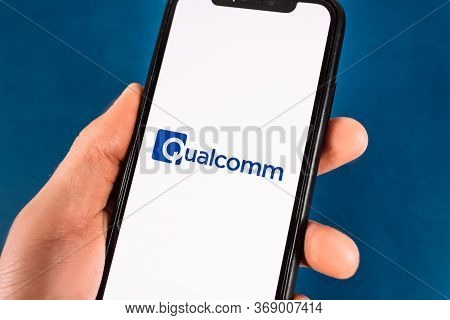 Hand Holds Smartphone With Qualcomm Logo. High Quality Photo.
