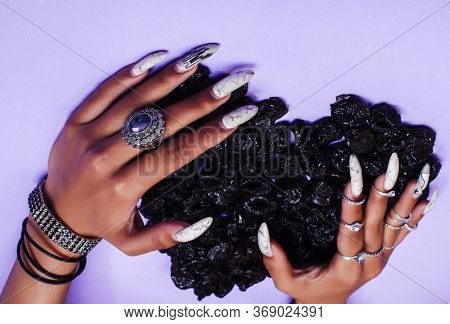 Woman Hands With Long Nails Manicure Holding Dry Fruits In Shape Of Heart On Purple Background