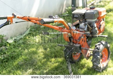 Man Farmer Plows The Land With A Cultivator. Agricultural Machinery: Cultivator For Tillage In The G