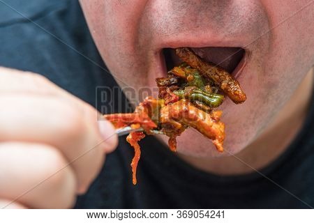 A Man Sends Fried Meat With Sauce From A Fork To His Mouth, Closeup.