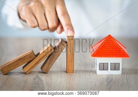 Woman Hand Stopping Risk The Wooden Blocks From Falling On House, Investment Risk And Uncertainty In