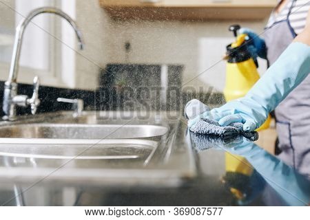 Close-up Image Of Woman Spraying Disinfecting Detergent On Kitchen Counter And Sink To Kill All Bact