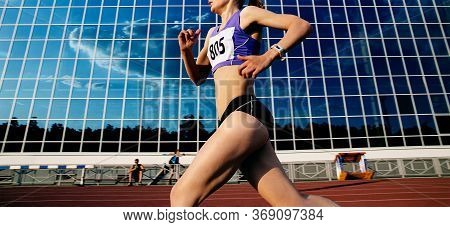 Girl Runner Run Stadium On Background Mirror Facade With Reflection Sky Blue