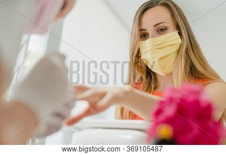 Woman with face mask during manicure in nail salon