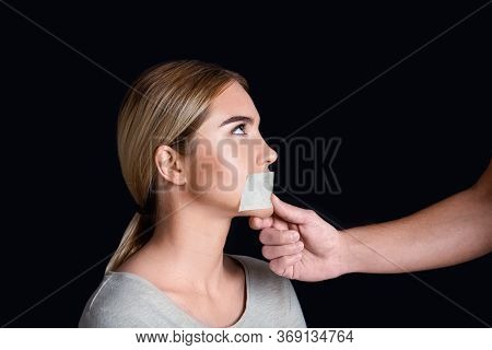 Discrimination And Tyranny. Man Covered Woman Mouth With Tape, Isolated On Black Background, Studio 