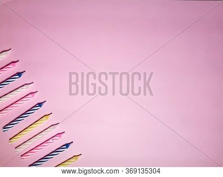 Multi-colored Birthday Candles On A Pink Background. Background For Birthday Or Anniversary Card Or 