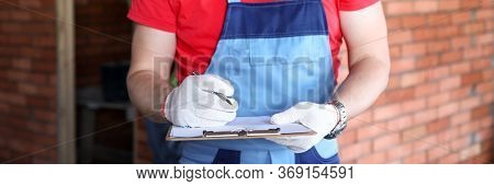 Close-up Of Professional Builder In Building Uniform. Male Person Holding Paper Folder With Informat