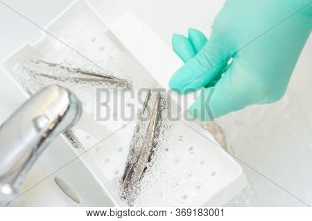Hand In Glove Cleans The Tweezers With Water In Tray. Cleaning Systems For Tweezers.