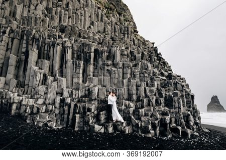 A Wedding Couple Stands On A Wall Of Stone Pillars. The Bride And Groom Are Hugging On Basalt Kekurs