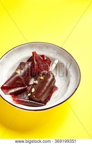 Chocolate mousse dessert close up. Luxury restaurant sweet course side view. Ice cream served with pastila in deep craft plate. Fancy confectionery dish with jellied fruit sweetmeat. Sweet food