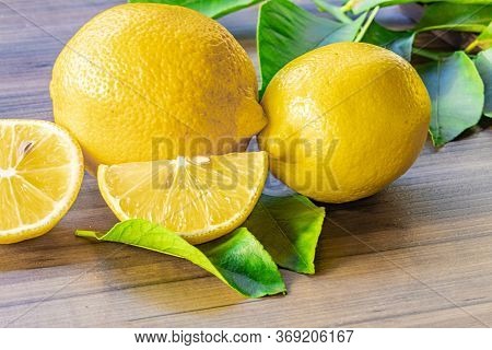 Top view of lemon and green leaves on wooden background