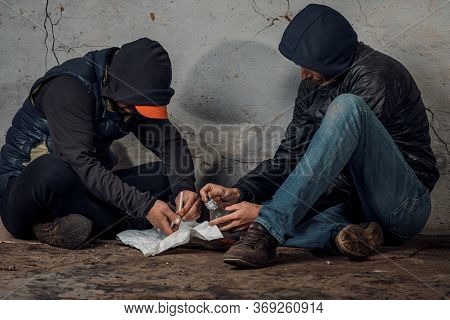 Two Shabby Men Preparing Drug Injection In Slums.
