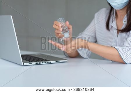 Business Woman Wearing Mask And Using Personal Sanitizer To Cleaning Her Hand In Office To Keep Hygi