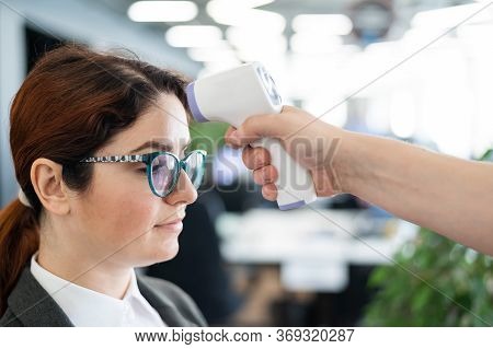 Temperature Measurement By Electronic Infrared Thermometer For Office Staff. Sick Woman In A Suit. C