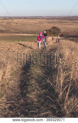 Mother And Kids On Their Bikes Go Up The Hill.