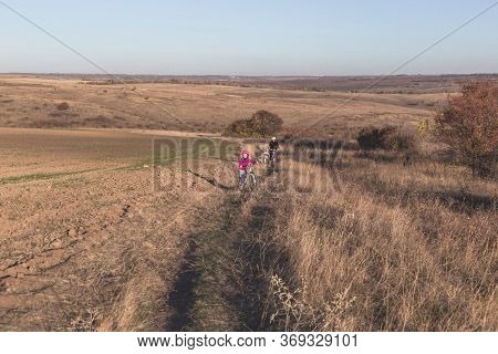 Mother And Kids On Their Bikes Go Up The Hill.