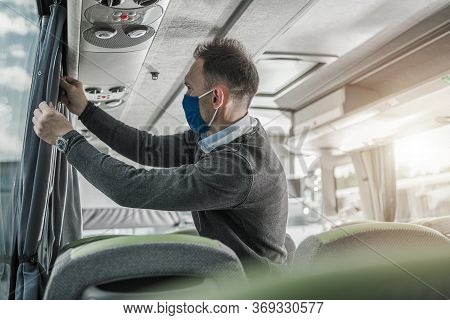 Caucasian Bus Coach Driver In His 30s Preparing His Vehicle For Another Trip. Checking On Window Cov