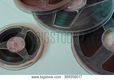 Several Plastic Bobbins Close-up. Old Bobbins With Audio Recordings In Multi-colored Rays On A Light