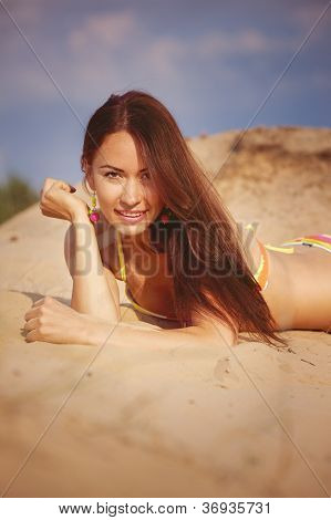 En smuk pige i en bikini hælder sand