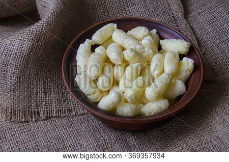 A Brown Clay Bowl Full Of Puffcorn. Ready To Eat Puffcorn. Crispy Sweet Treats On Burlap.
