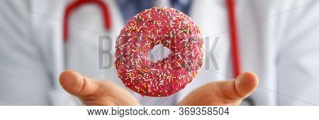 Doctor In Office Holding In Hand Pink Doughnut Close-up. Products That Can Not Be Consumed In Certai