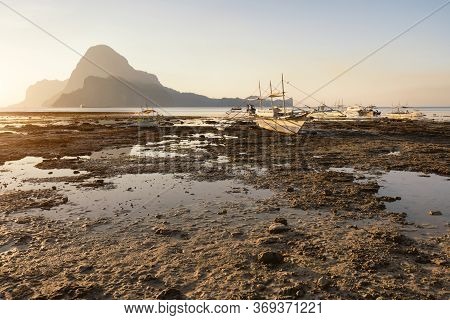El Nido, Banca Boat In Low Tide. Sunset Behind Beautiful Cadlao Island. Palawan Island, Philippines