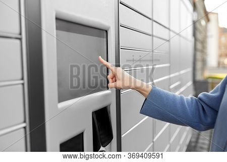 mail delivery and post service concept - close up of woman's hand choosing operation on outdoor automated parcel machine's touch screen