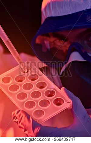COVID-19 or 2019-nCoV. Close-up portrait of a scientist microbiologist in a protective PPE suit making a research on blood samples of infected people.