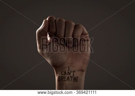 closeup of the raised fist of a man with the text I cant breathe in his wrist, as it is used as slogan in the anti-racist protests in the United States