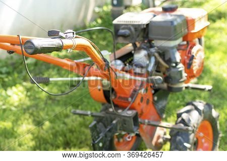 Man Farmer Plows The Land With A Cultivator. Agricultural Machinery: Cultivator For Tillage In The G