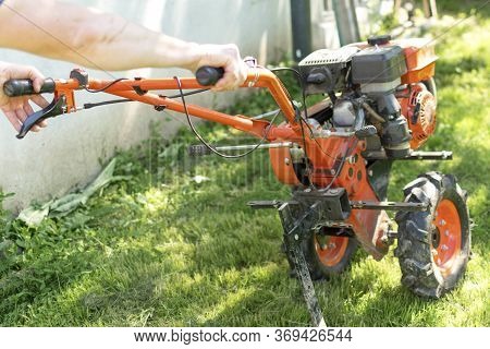Man Farmer Plows The Land With A Cultivator. Agricultural Machinery: Cultivator For Tillage In The G