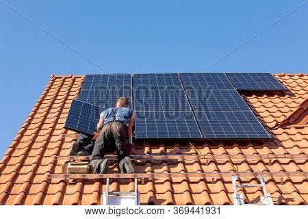 Workers Installing Solar Electric Panels On A House Roof In  Ochojno. Poland