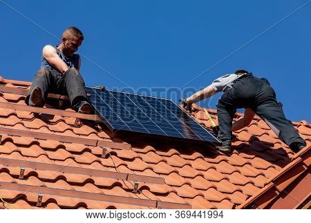 Ochojno, Poland - April 8, 2020: Workers Installing Solar Electric Panels On A House Roof In  Ochojn