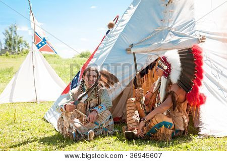 North American Indians sit at a wigwam