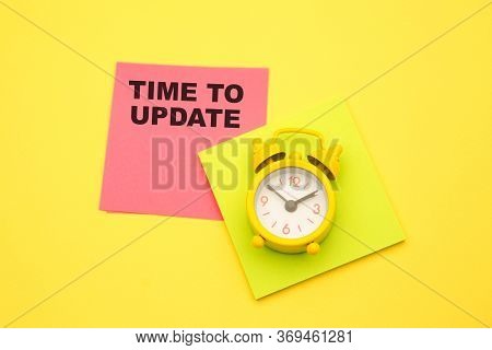 Top View Of Alarm Clock And Colorful Sticker With Time To Update On Yellow Background