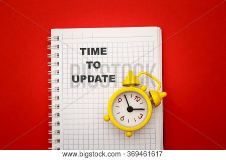 Yellow Alarm Clock And Notebook With Time To Update On Red Background