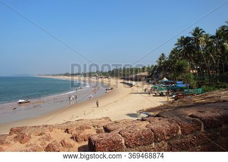 Goa, India-january 7, 2017. People Walk Through The Beach Sinquerim Along The Coastline. Tourists An