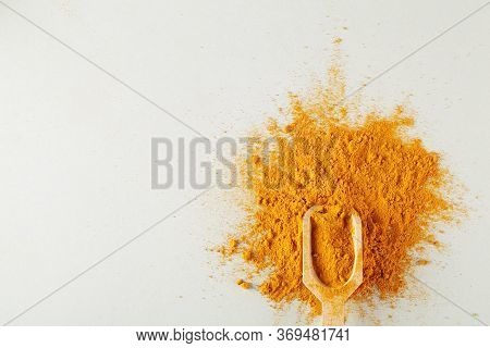 Turmeric Powder In Wood Spoon On Gray Background